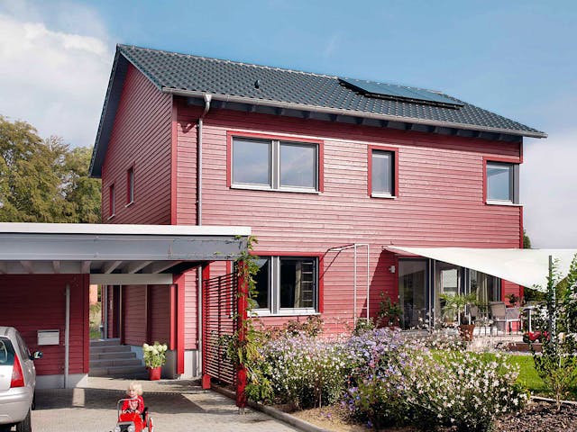 Einfamilienhaus E 20-148.6 von SchwörerHaus mit roter Fassade und Satteldach als Fertighaus mit 137 m²